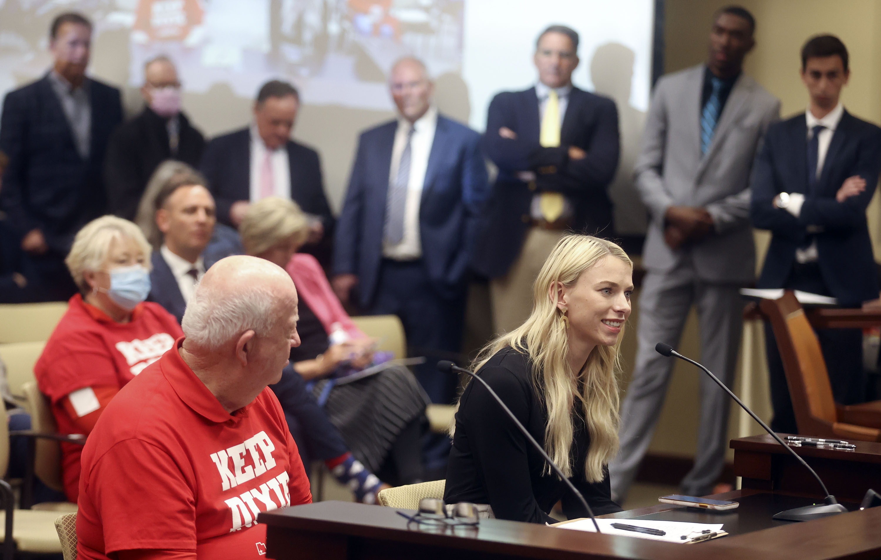 Morgan Olson, a junior at Dixie State University, speaks in support of changing the university’s name to Utah Tech during an Education Interim Committee hearing in the House Building at the Capitol complex in Salt Lake City on Tuesday. Others are lined up to speak behind her.