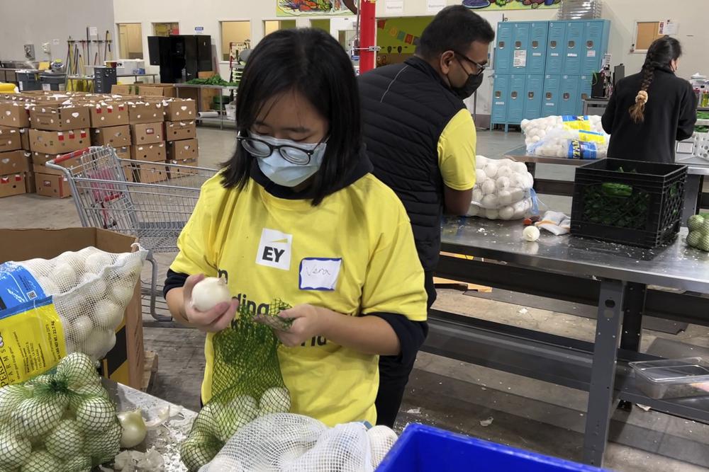 A volunteer packs onions in the warehouse of the Alameda County Community Food Bank in Oakland, Calif., on Friday. U.S. food banks dealing with increased demand from families sidelined by the pandemic now face a new challenge — surging food prices and supply chain issues.