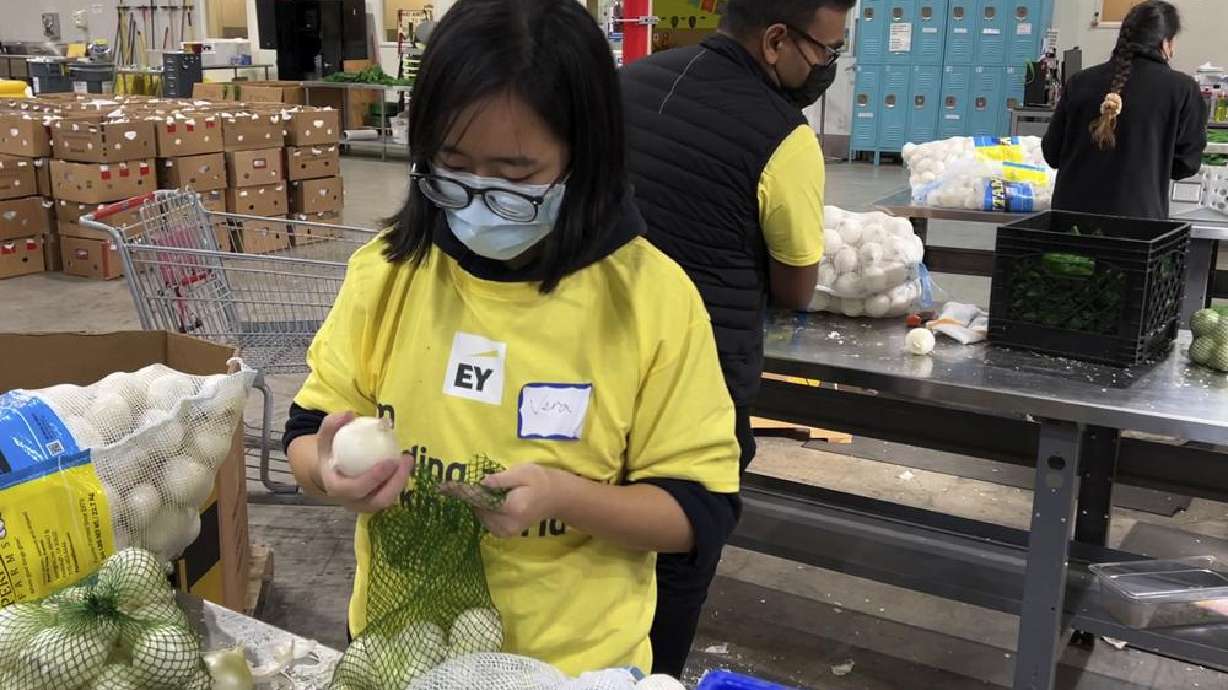 A volunteer packs onions in the warehouse of the Alameda County Community Food Bank in Oakland, Calif., on Friday. U.S. food banks dealing with increased demand from families sidelined by the pandemic now face a new challenge — surging food prices and supply chain issues.