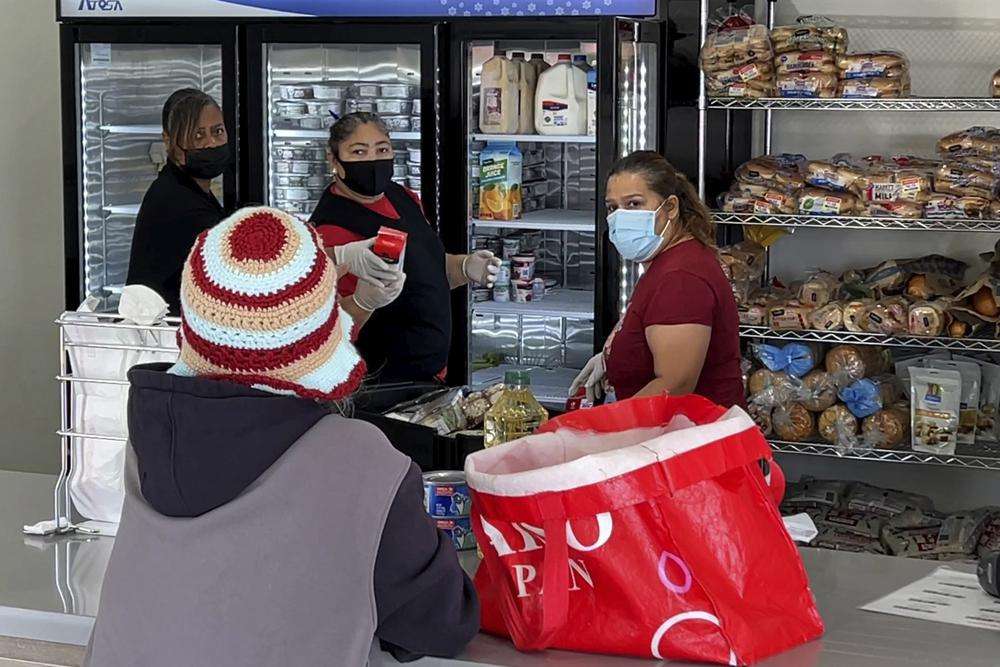 Staff members pick out free groceries for a customer at a food pantry at Shiloh Mercy House in Oakland, Calif., on Thursday. U.S. food banks dealing with increased demand from families sidelined by the pandemic now face a new challenge – surging food prices and supply chain issues. As holidays approach, some food banks worry they won't have enough turkeys, stuffing and cranberry sauce for Thanksgiving and Christmas.