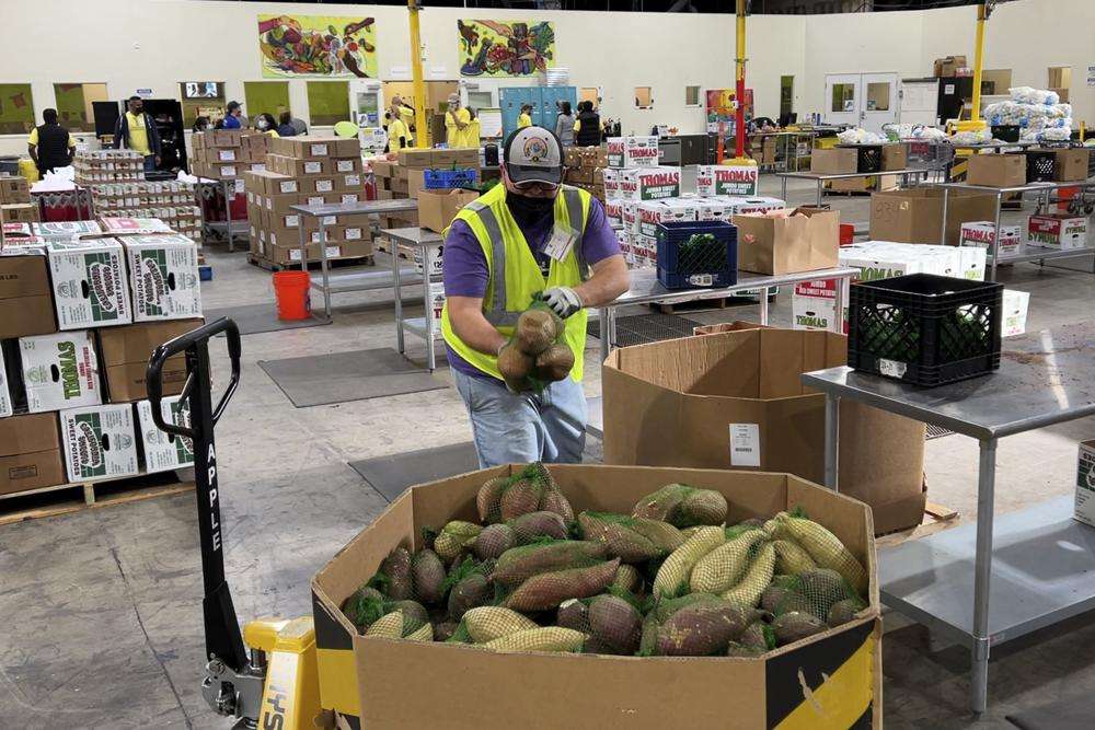 A worker puts bags of sweet potatoes in a container in the warehouse of the Alameda County Community Food Bank in Oakland, Calif., on Thursday. U.S. food banks dealing with increased demand from families sidelined by the pandemic now face a new challenge – surging food prices and supply chain issues.
