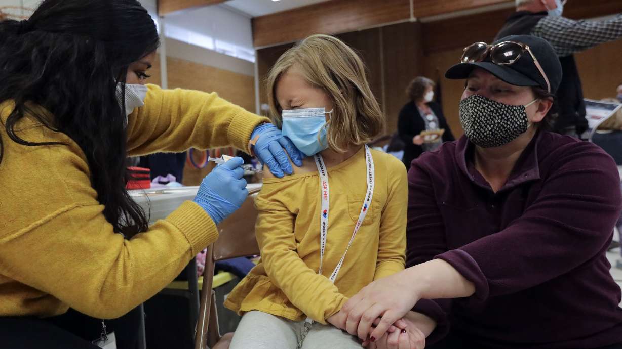 Claudia Ceron gives Etta Bastian, 7, a COVID-19 vaccination as Etta’s mother, Courtney Bastian, holds her hand at Hillsdale Elementary School in West Valley City on Monday. The Utah Department of Health reported 1,531 new COVID-19 cases and 12 deaths on Wednesday