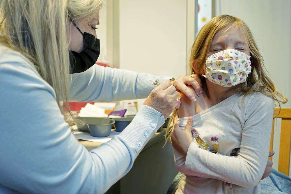 Shauna Andrus, left, a nurse volunteering at the University of Washington Medical Center, gives the first shot of the Pfizer COVID-19 vaccine to Emmy Slonecker, 7, Tuesday, in Seattle.
