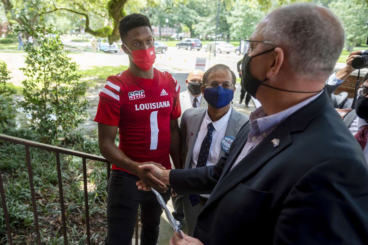 Louisiana quarterback Levi Lewis greets Gov. John Bel Edwards as he tours the University of Louisiana campus vaccination site as part of the university's Shot for $100 campaign in Lafayette, La., Aug. 19. Universities that adopted COVID-19 vaccine mandates this fall of 2021, have seen widespread compliance.