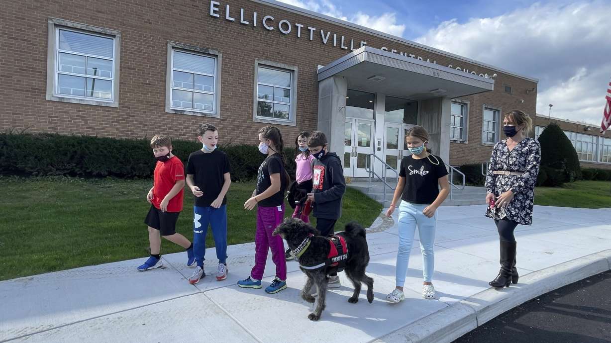 Students from Ellicottville Central Schools in Ellicottville, N.Y., walk therapy dog Toby outside the rural school on Oct. 21 accompanied by the dog's owner, elementary school principal Maren Bush, right. Bush lets students walk and visit with Toby as part of the district's efforts to improve students' mental well-being, a focus of schools nationwide following pandemic disruptions.