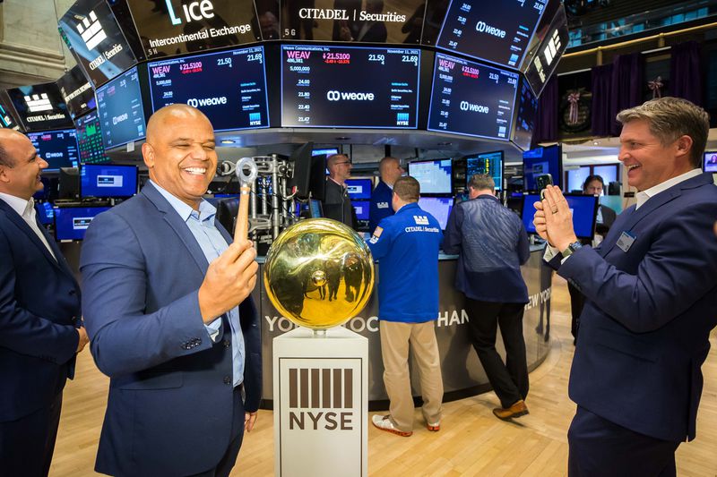 Weave CEO Roy Banks, left, is pictured on the floor of
the New York Stock Exchange. Weave began trading on the exchange on
Thursday.