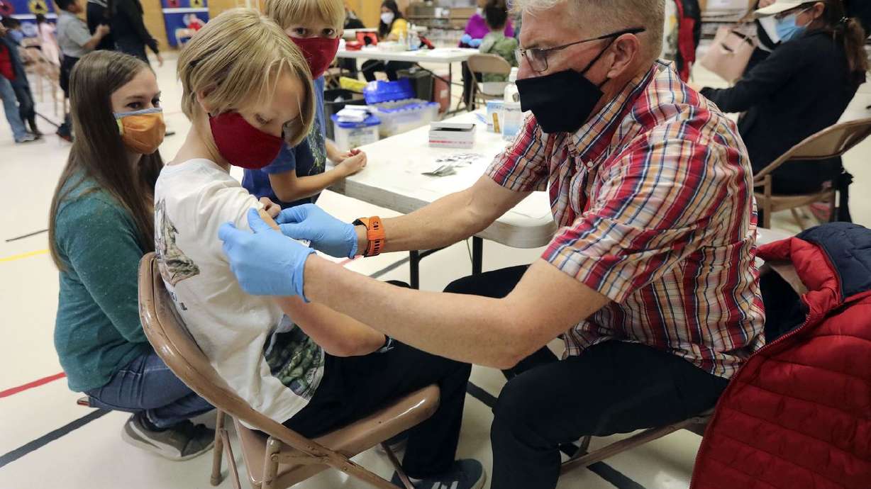 Maika Parker, left, and son Graham Parker watch as their son and brother, Trey Parker, gets a bandage from Curtis
Evans, a Salt Lake County Health Department community health worker and temporary vaccinator, after getting vaccinated on Nov. 8. Utah health officials confirmed 1,153 new COVID-19 cases on Tuesday, as well as 15 additional deaths.