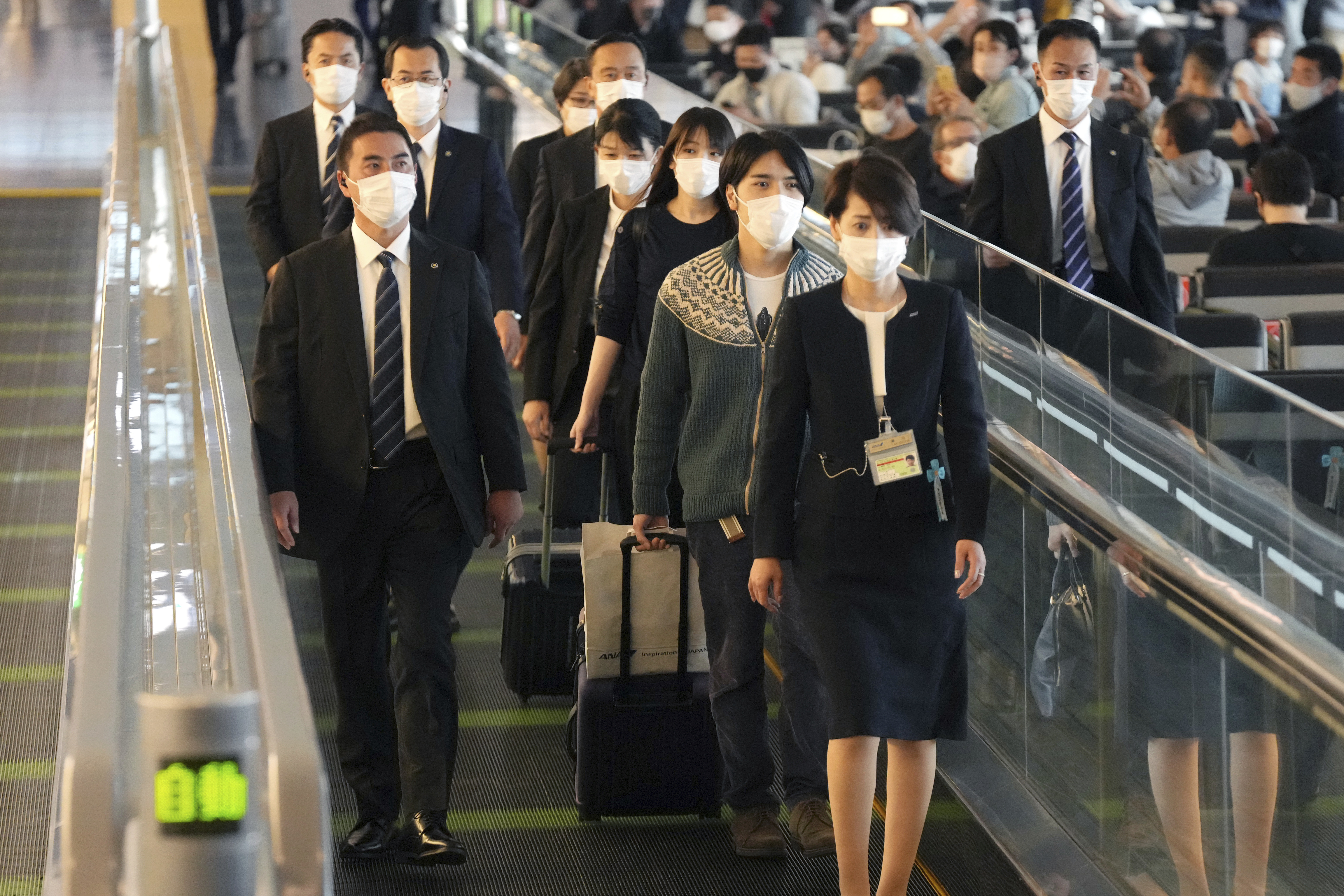 Japan's former Princess Mako, third right, the elder daughter of Crown Prince Akishino, and her husband Kei Komuro, second right, are escorted to board an airplane to New York Sunday, Nov. 14, 2021, at Tokyo International Airport in Tokyo.
