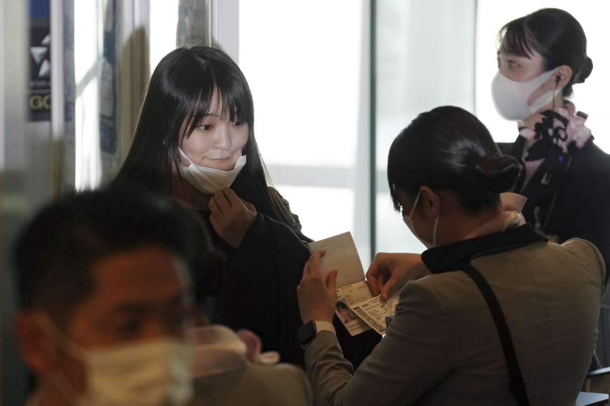 Japan's former Princess Mako, left, the elder daughter of Crown Prince Akishino, takes her mask off at a boarding gate to board an airplane to New York with her husband Kei Komuro, not in picture, Sunday, Nov. 14, 2021, at Tokyo International Airport in Tokyo.