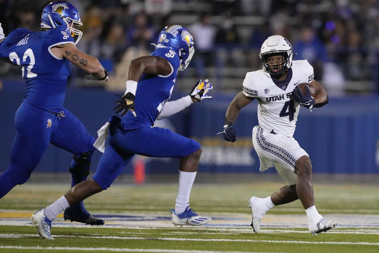 Utah State running back Calvin Tyler Jr. (4) rushes against San Jose State safety Jay Lenard (27) and defensive lineman Cade Hall (92) during the first half of an NCAA college football game Saturday, Nov. 13, 2021, San Jose, Calif.