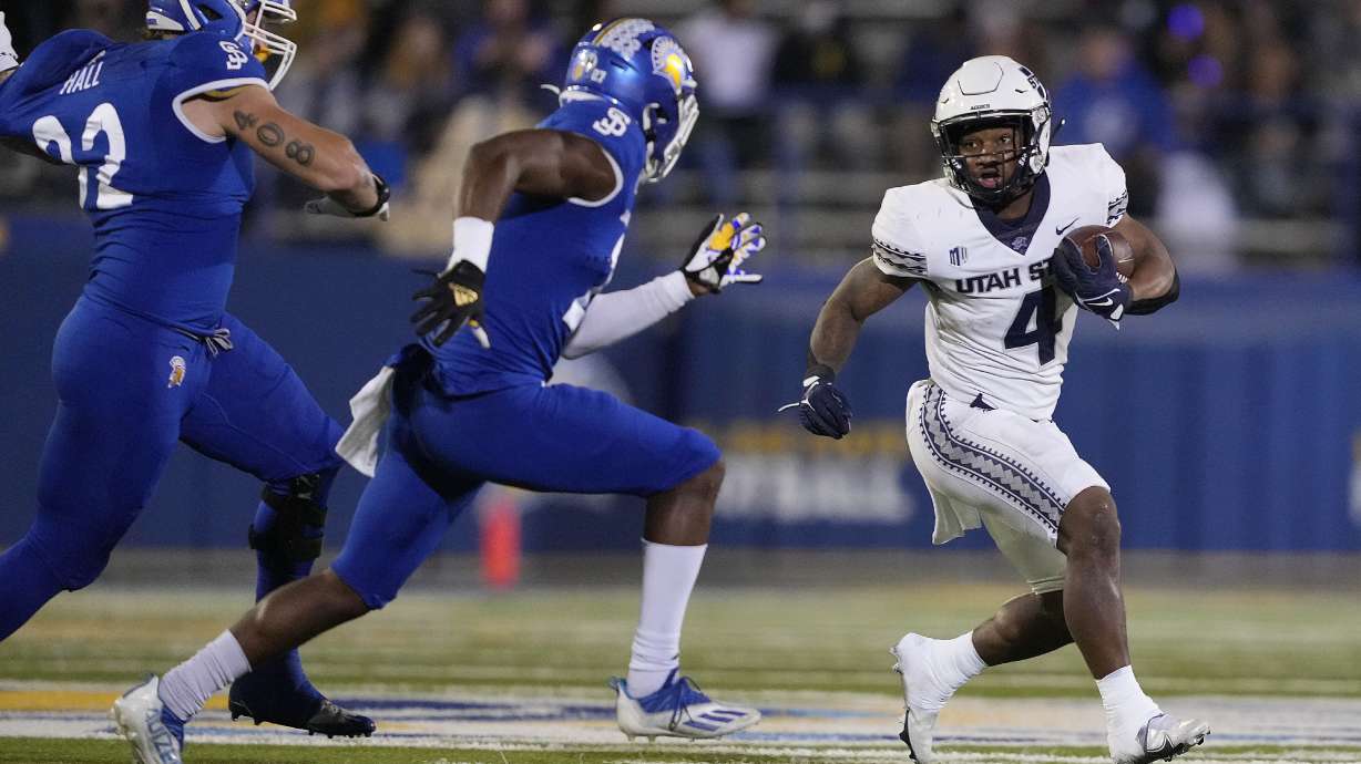 Utah State running back Calvin Tyler Jr. (4) rushes against San Jose State safety Jay Lenard (27) and defensive lineman Cade Hall (92) during the first half of an NCAA college football game Saturday, Nov. 13, 2021, San Jose, Calif.