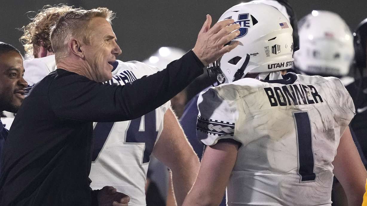 Utah State head coach Blake Anderson, left, tabs quarterback Logan Bonner (1) on the head after he threw a touchdown pass against San Jose State during the second half of an NCAA college football game Saturday, Nov. 13, 2021, San Jose, Calif. Utah State won 48-17.