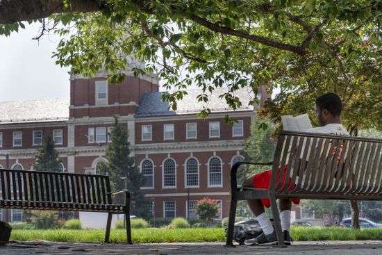 With the Founders Library in the background, a young man reads on Howard University campus July 6, 2021, in Washington. Nationwide, American colleges and universities saw a 4% annual increase in international students this fall, according to survey results released Monday by the Institute of International Education. But that follows a decrease of 15% last year, the steepest decline since the institute began publishing data in 1948.
