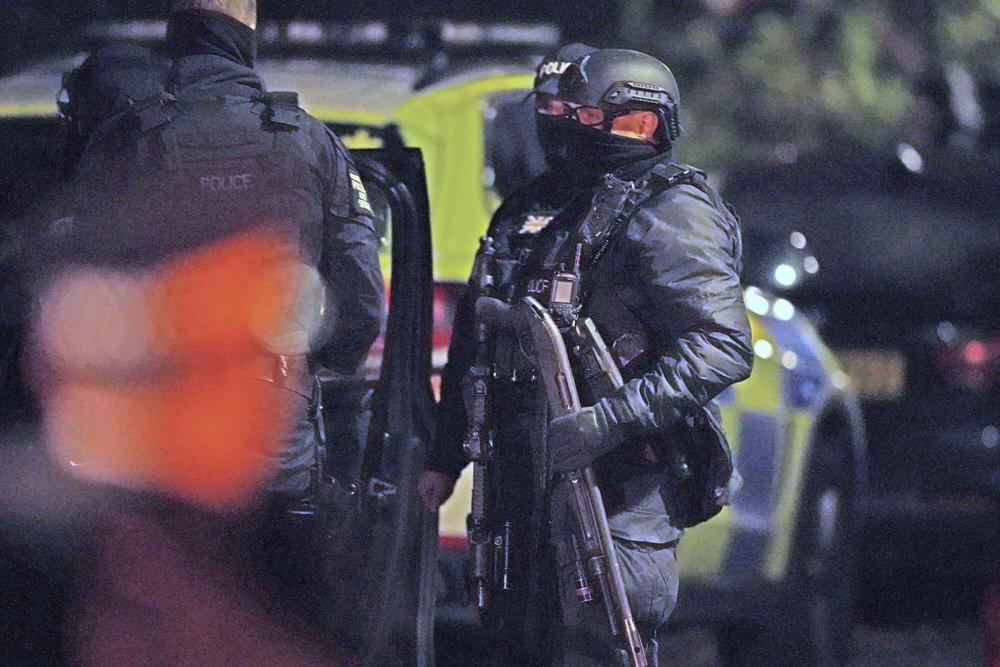 An armed police officer holds a breaching shotgun, used to blast the hinges off a door, at an address in Rutland Avenue in Sefton Park, after an explosion at the Liverpool Women's Hospital in Liverpool, England, Monday. British police arrested three men under terrorism laws Sunday after a car exploded outside the hospital, killing one man and injuring another. 