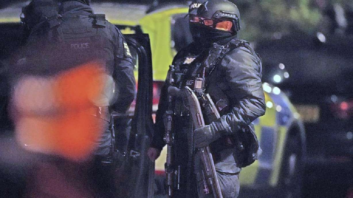 An armed police officer holds a breaching shotgun, used to blast the hinges off a door, at an address in Rutland Avenue in Sefton Park, after an explosion at the Liverpool Women's Hospital in Liverpool, England, Monday. British police arrested three men under terrorism laws Sunday after a car exploded outside the hospital, killing one man and injuring another.