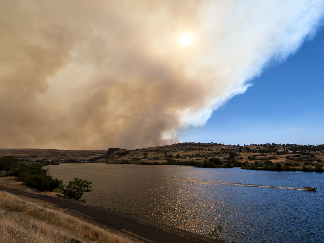 A boat heads down the Snake River as smoke from the
Asotin Complex Fire west of Clarkston, Washington, wafts eastward into
Lewiston, Idaho, on July 7. The sunny skies and pleasant fall
afternoons may bode well for your mental health, but they’re not
going to help you when it comes to next year’s irrigation season.