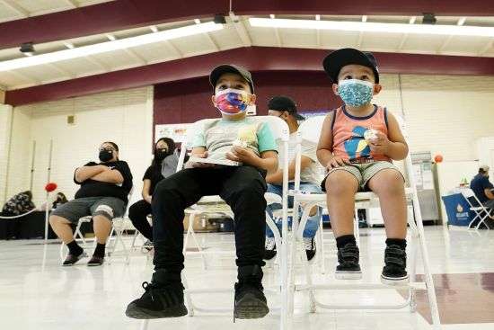 Oliver Estrada, 5, front left, waits with his brother Adriel, 2, after Estrada received the first dose of the Pfizer COVID-19 vaccine at an Adelante Healthcare community vaccine clinic at Joseph Zito Elementary School, Nov. 6, 2021, in Phoenix. Health systems have released little data on the racial breakdown of youth vaccinations, and community leaders fear that Black and Latino kids are falling behind.