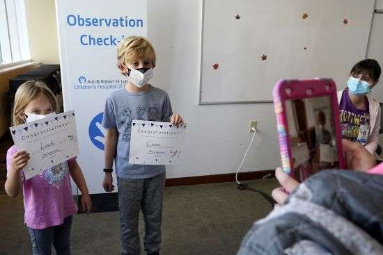 Leah Malloy, 6, left, and her brother Owen Malloy, 9, take photos with the COVID-19 vaccine certificate after receiving the Pfizer COVID-19 vaccine for children 5 to 11 years as Lurie Children's hospital registered nurse Jeanne Bailey, right, looks on at Lurie Children's hospital on Nov. 5, in Chicago.Health systems have released little data on the racial breakdown of youth vaccinations, and community leaders fear that Black and Latino kids are falling behind.