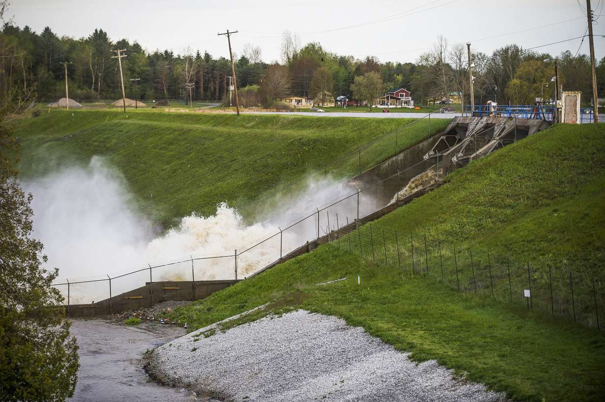 Water rushes through the Edenville Dam on May 19, 2020, in Edenville, Mich. Federal money is poised to flow to states to address a pent-up need to repair, improve or remove thousands of aging dams across the U.S., including some that could devastate downstream towns or neighborhoods. The money is included in a $1 trillion infrastructure bill signed by President Joe Biden and is significantly more than has gone to dams in the past.