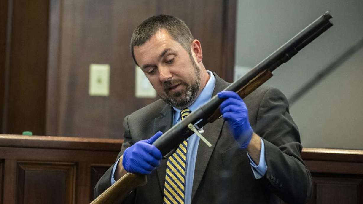 Firearms expert Brian Leppard with the Georgia Bureau of Investigation examines a 12-gauge Remington pump shotgun as part of evidence during the trial of Greg McMichael and his son, Travis McMichael, and a neighbor, William "Roddie" Bryan in the Glynn County Courthouse, Monday, in Brunswick, Georgia. The three are charged with the February 2020 slaying of 25-year-old Ahmaud Arbery.