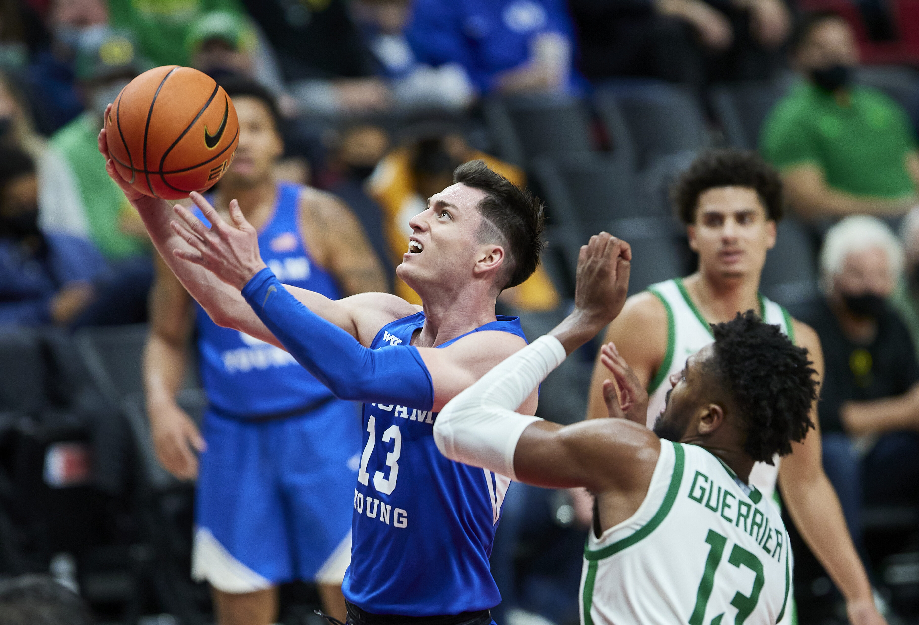 BYU guard Alex Barcello, left, shoots next to Oregon forward Quincy Guerrier during the second half of an NCAA college basketball game in Portland, Ore., Tuesday, Nov. 16, 2021.