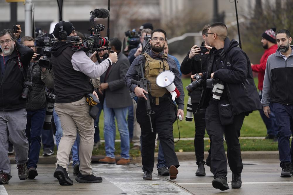 A protester carrying a rifle leaves the the Kenosha County Courthouse after speaking with Kenosha County Sheriffs Department officers, Wednesday in Kenosha, Wis., during the Kyle Rittenhouse murder trial. Rittenhouse is accused of killing two people and wounding a third during a protest over police brutality in Kenosha in 2020.