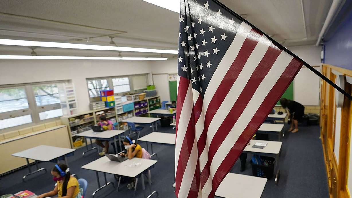 An American flag hangs in a classroom as students work on laptops in Newlon Elementary School in Denver early on Tuesday,
Aug. 25, 2020. The school is one of 55 Discovery Link sites set up by Denver Public Schools where students are participating in remote learning. From Denver’s largest school district to small, rural districts elsewhere in the West, school staffing shortages are exacting a toll.