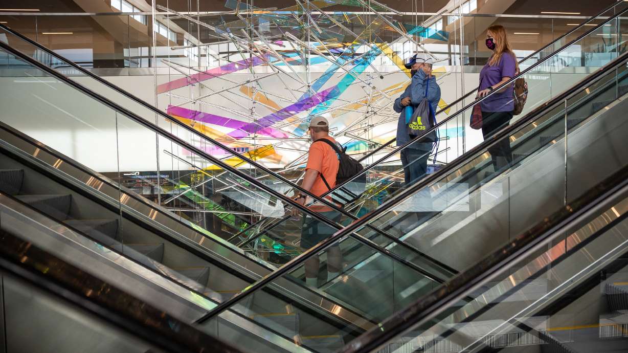Travelers ride an escalator past “The Falls,” an art installation by Gordon Huether, at Salt Lake International Airport in Salt Lake City on Nov. 18. The airport is slated to receive another $24.7 million in infrastructure spending for the 2022 fiscal year.