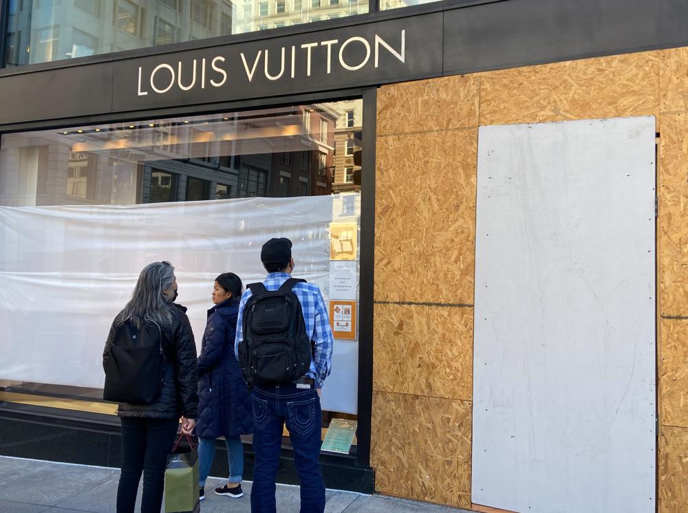 Union Square visitors look at damage to the Louis Vuitton store on Sunday, after looters ransacked businesses late Saturday night in San Francisco.