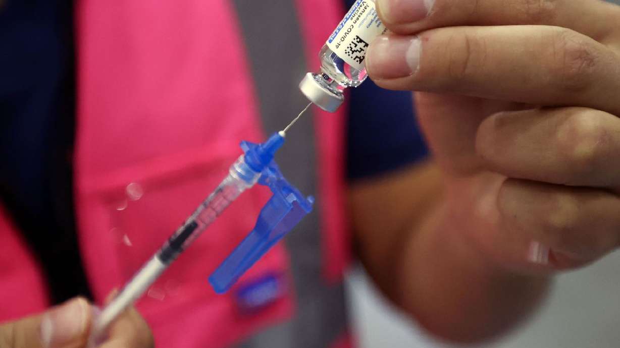 Davis County community health nurse Bruno Gonzalez gets
a vial of the Johnson & Johnson COVID-19 vaccine to prepare
booster doses at the Legacy Events Center in Farmington on
Oct. 25.
