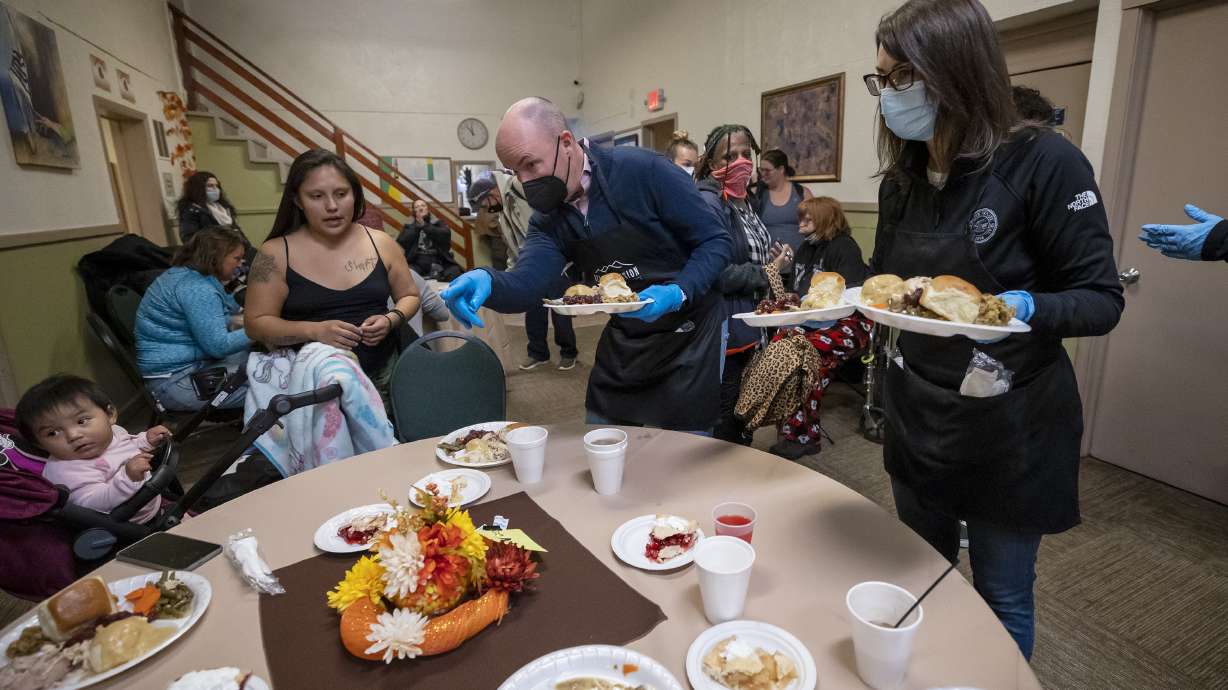 Utah Gov. Spencer Cox, center, and Lt. Gov. Deidre Henderson, left, serve a Thanksgiving meal to Rosalinda Segura, left, and her mother, Keisha Atcitty, at the Rescue Mission of Salt Lake in Salt Lake City on Monday.