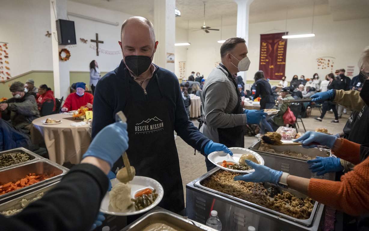 Utah Gov. Spencer Cox holds plates as volunteers put food on them during a Thanksgiving dinner at the Rescue Mission of Salt Lake in Salt Lake City on Monday.
