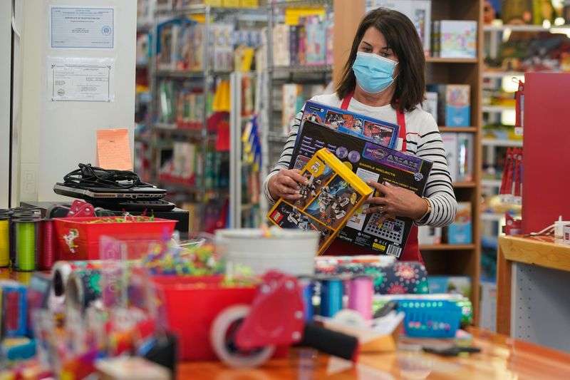 Sue Mcgill, an employee at Tutoring Toy in Salt Lake
City, carries toys while helping a customer ahead of Thanksgiving
on Monday.