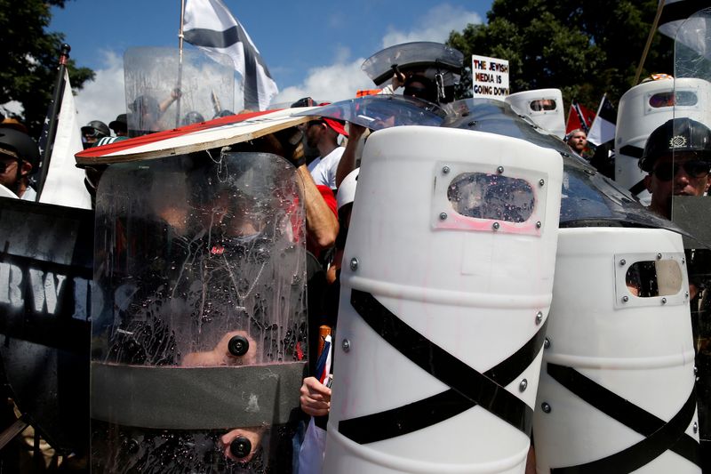 White nationalists shelter behind shields, displaying the Southern Nationalist flag, after clashing with counter protesters at a rally in Charlottesville, Va., on Aug. 12, 2017.