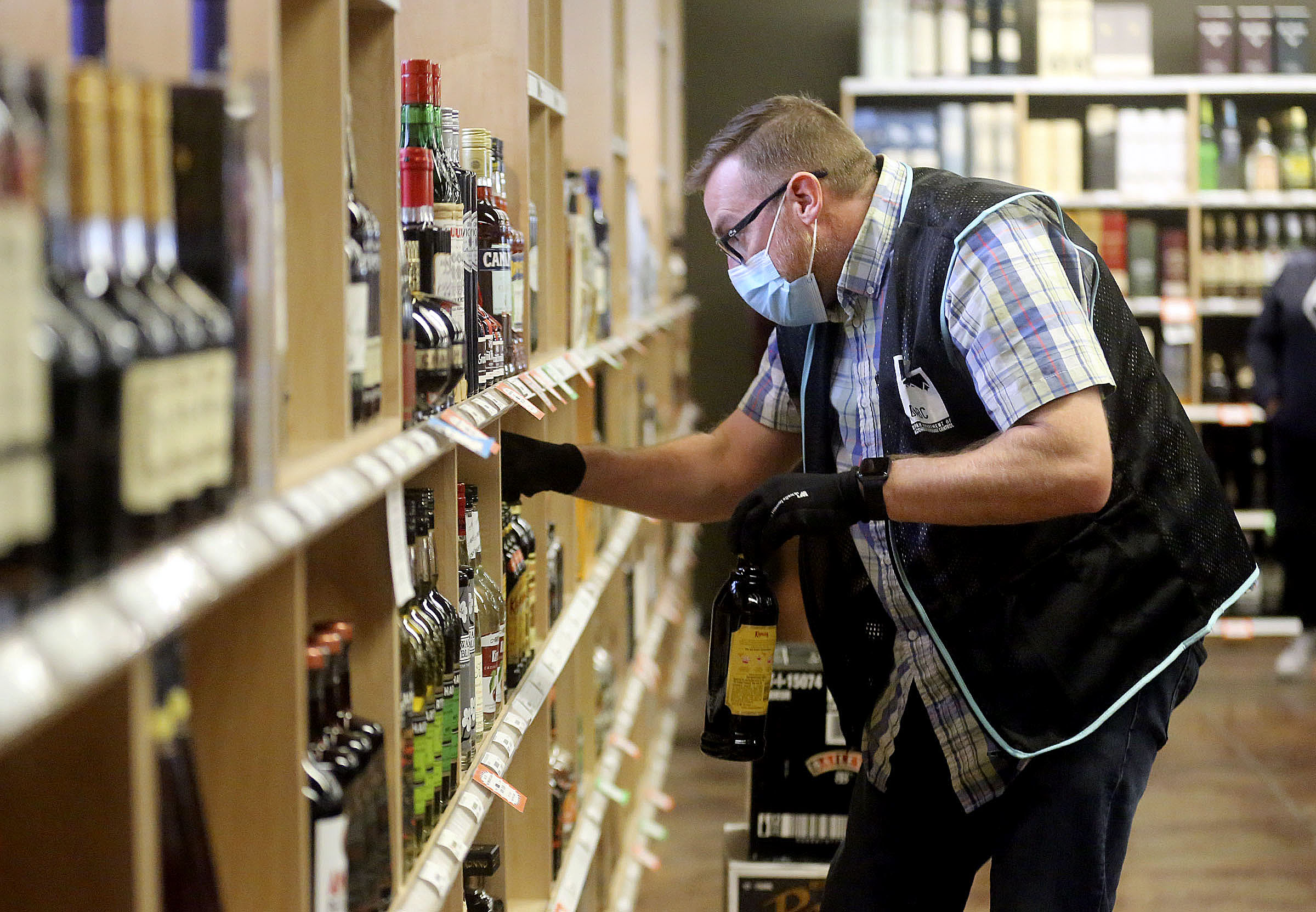 Justin Robertson, a full-time staffer, stocks the shelves at a state liquor store in Salt Lake City on Friday, Oct. 23, 2020.