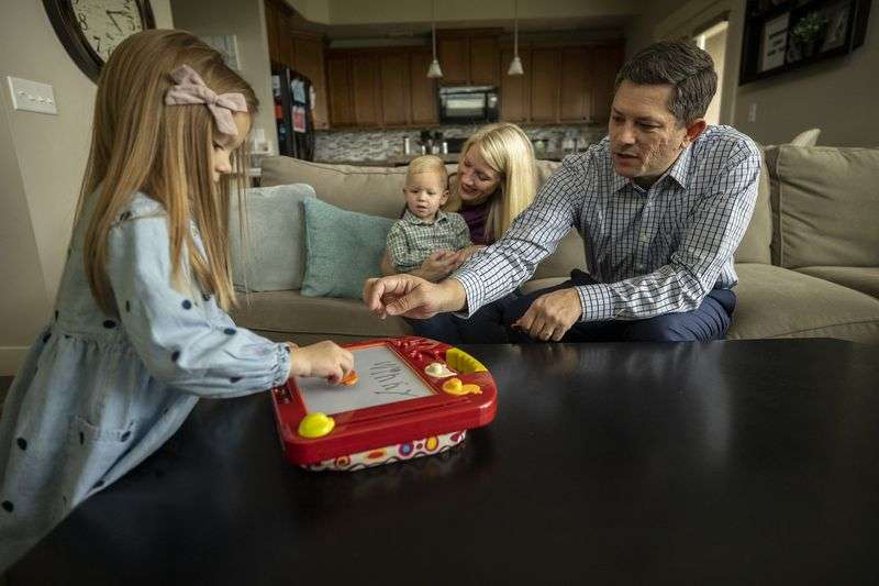 Winny Britton left, plays with her father, Cory, right,
as her mother, Karin, holds her brother, Alexander, after posing
for photos at their home in Riverton on Tuesday, April 27, 2021.
Cory Britton, 37, has a degree in computer engineering from Weber
State University.