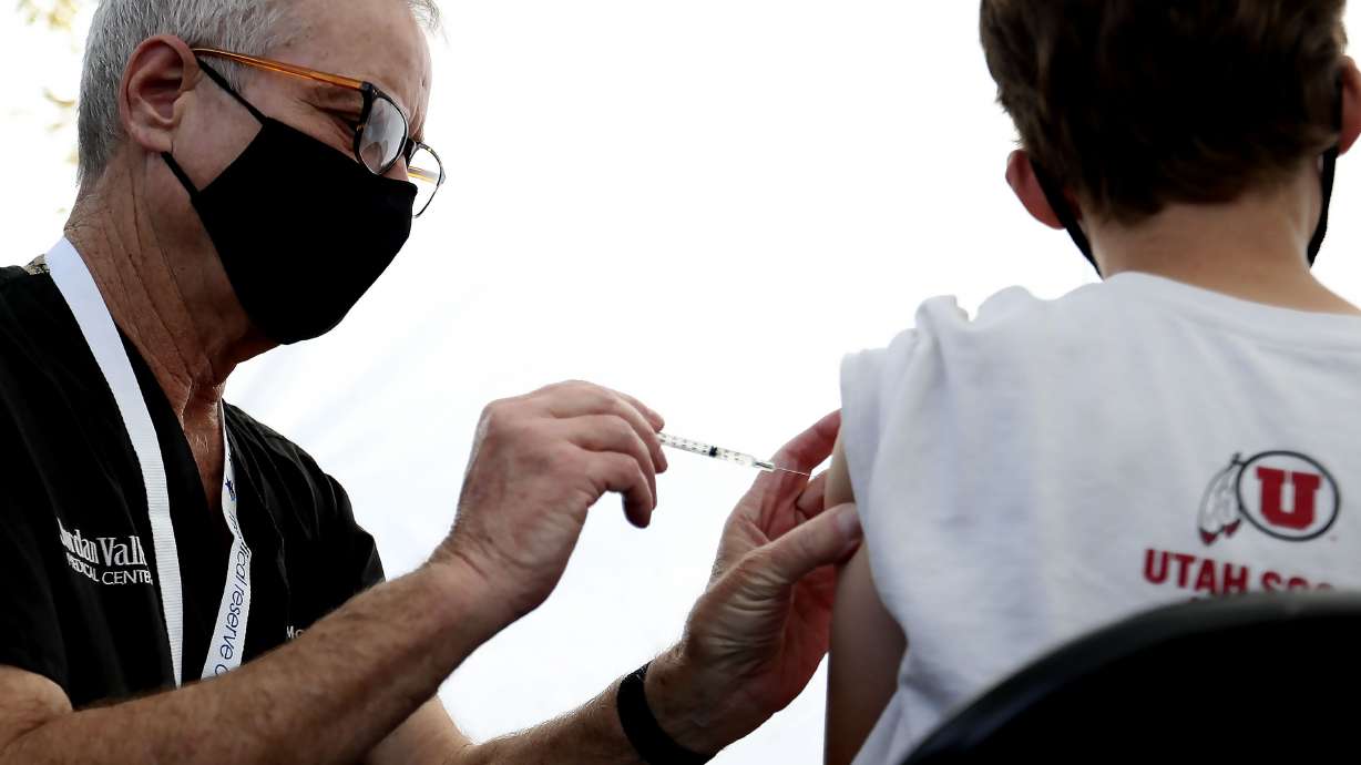 David McKay administers a COVID-19 vaccination to a 12-year-old boy at Rose Park Elementary in Salt Lake City on Sept. 22, 2021. Utah health care officials reported 543 new COVID-19 cases since Friday, as well as nine additional deaths.