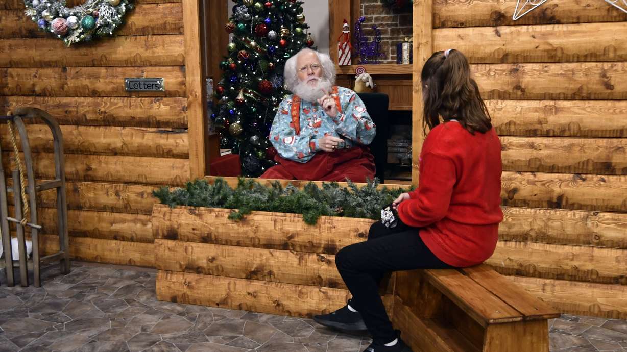 Santa, Sid Fletcher, sits behind a glass barrier as he hears Kendra Alexander of St. James, Minn., during her visit Nov. 15, at The Santa Experience at the Mall of America in Bloomington, Minnesota.
