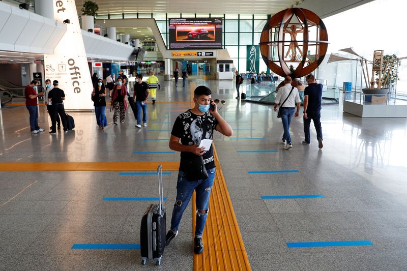 A passenger wearing a protective face mask talks on the phone at Fiumicino Airport on the day EU governments agreed a "safe list" of 14 countries for which they will allow nonessential travel starting from July, following the coronavirus disease outbreak, in Rome, Italy, June 30, 2020.