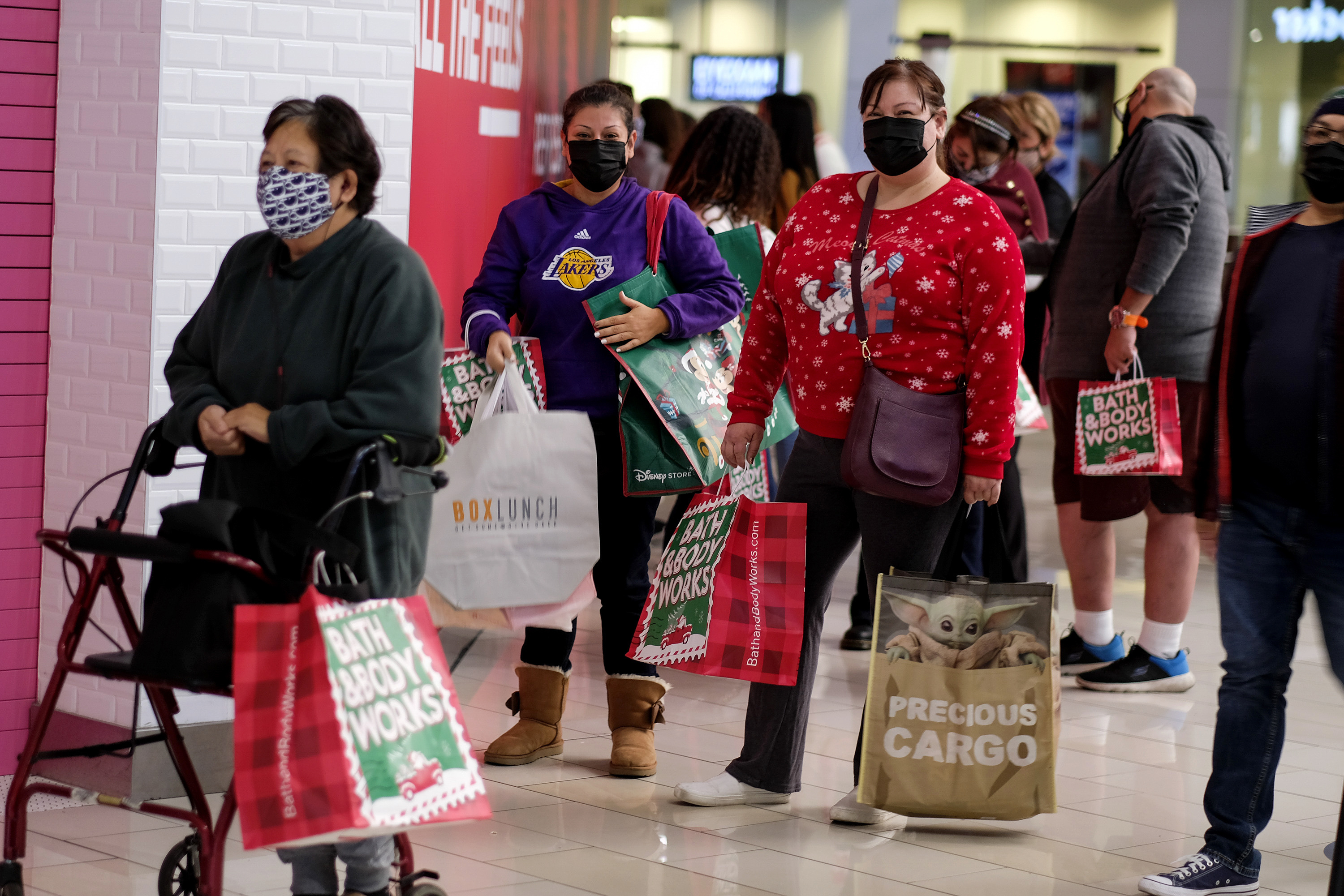 Black Friday shoppers wearing face masks wait in line to enter a store at the Glendale Galleria in Glendale, Calif., on Nov. 27, 2020. Retailers are expected to usher in the unofficial start to the holiday shopping season Friday with bigger crowds than last year.