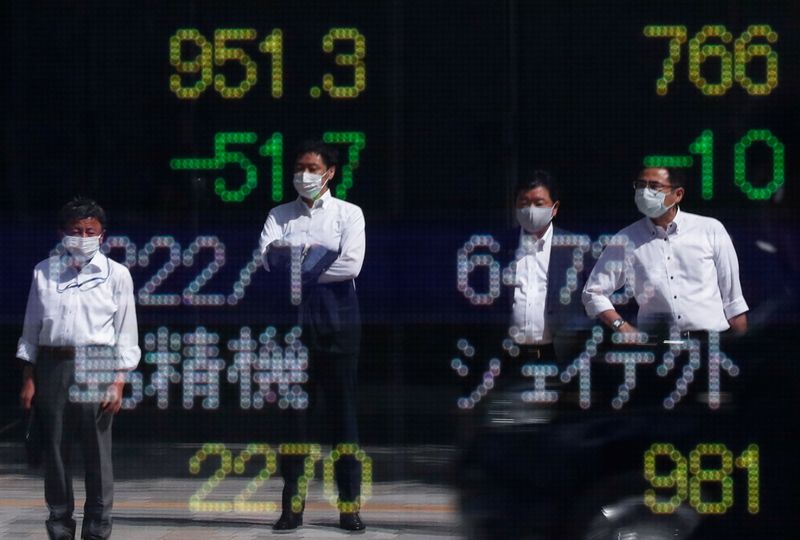 Passersby wearing protective masks are reflected on an electronic board displaying stock prices outside a brokerage amid the coronavirus disease outbreak, in Tokyo, Japan, Sept. 29.