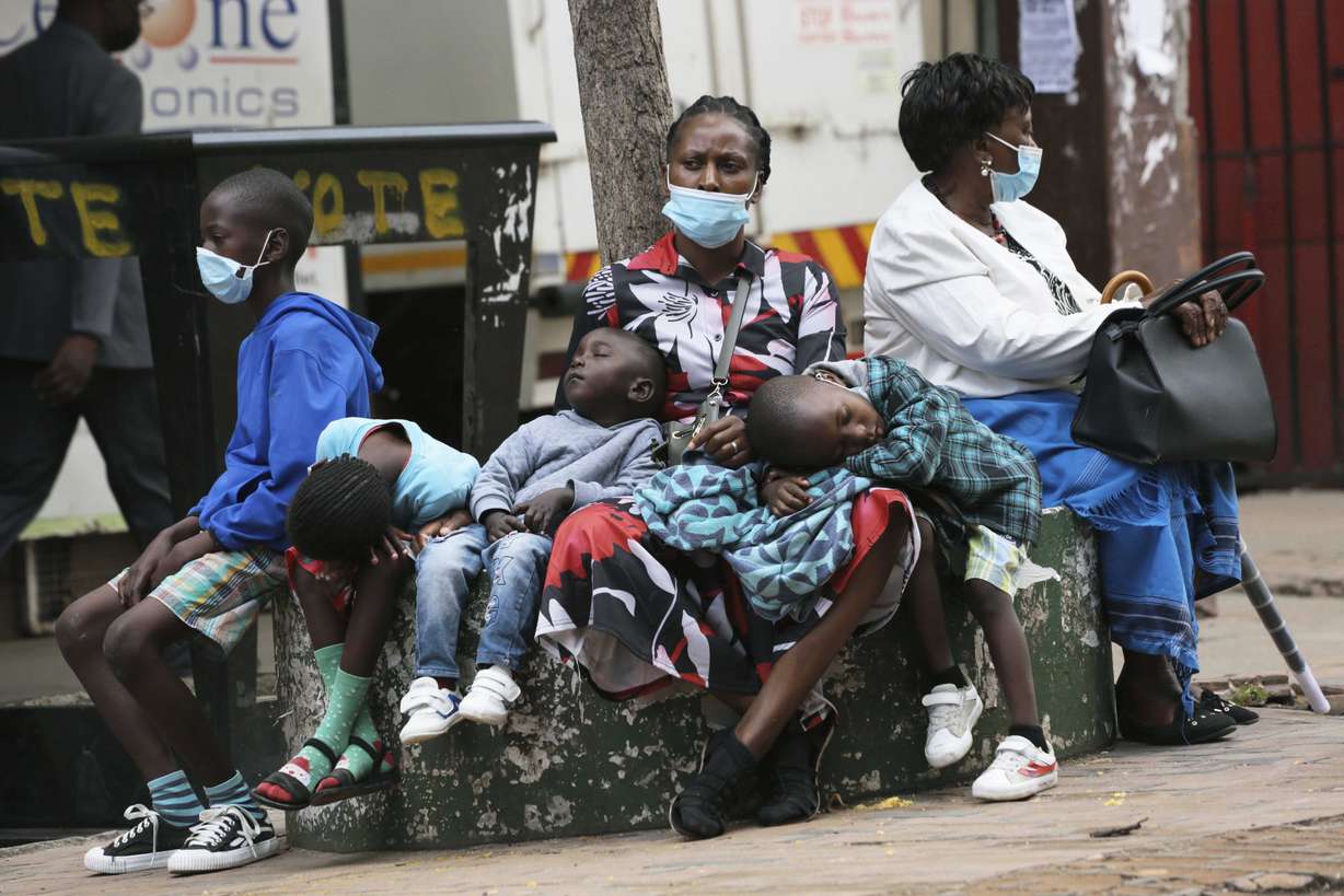 A mother takes time to rest with her children in Harare, Zimbabwe, Friday. A slew of nations have moved to stop air travel from southern Africa, and stocks have plunged in Asia and Europe in reaction to news of a new, potentially more transmissible COVID-19 variant.