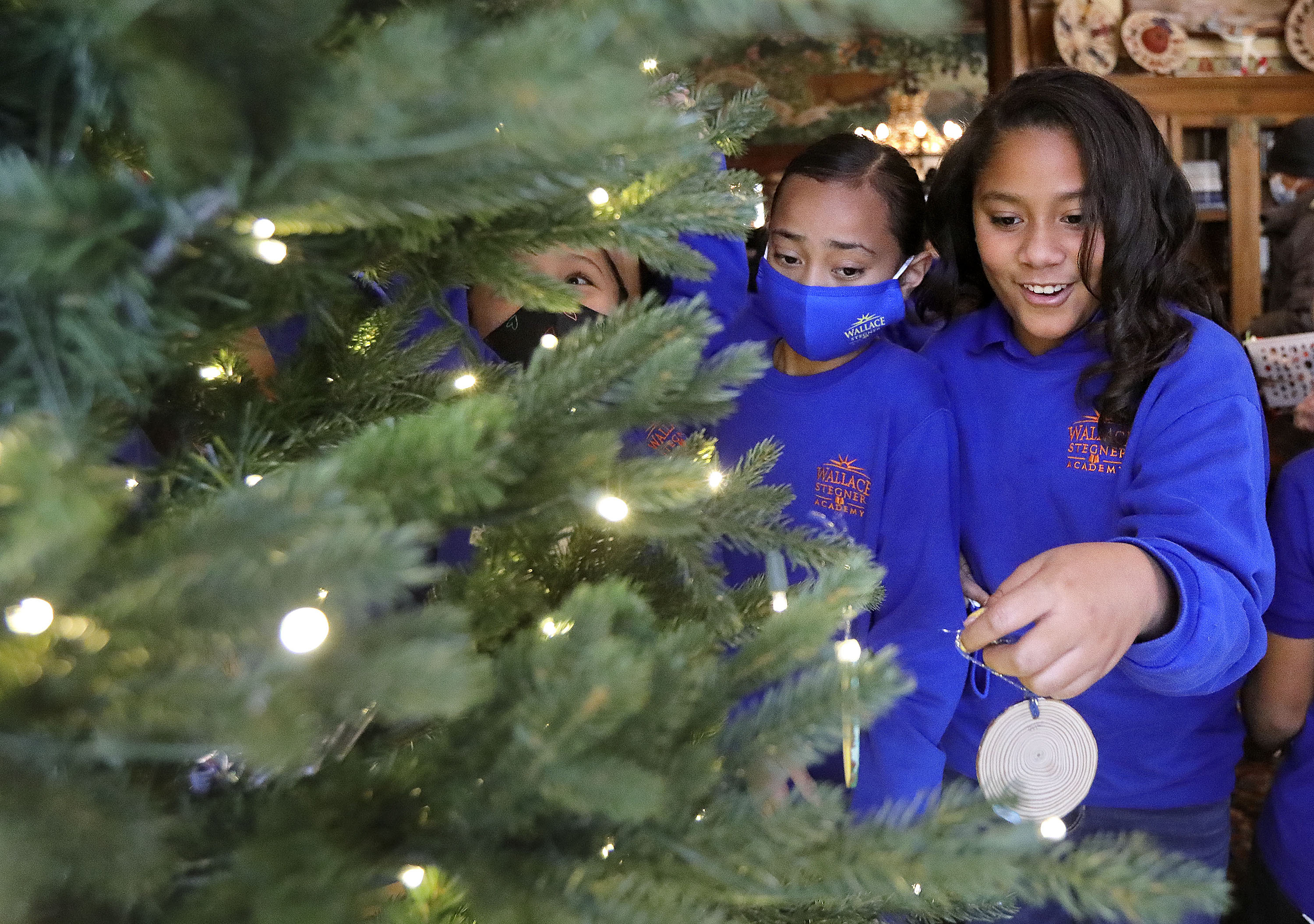 Diana Katoa and Leilana Sua decorate a Christmas tree with other fourth graders from Wallace Stegner Academy, using ornaments they made, at the Governor’s Mansion in Salt Lake City on Monday.
