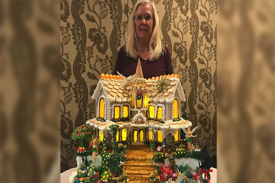 Geri Hansen stands behind one of the 27 gingerbread houses she’s made since 2014.
