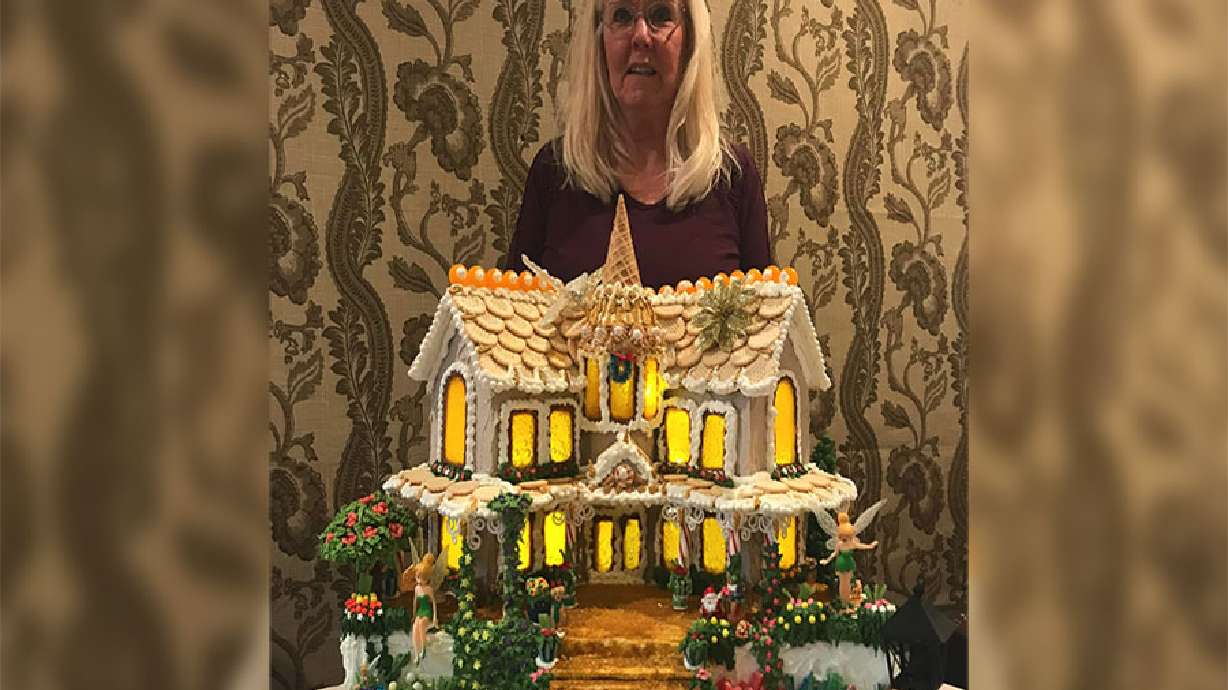 Geri Hansen stands behind one of the 27 gingerbread houses she’s made since 2014.