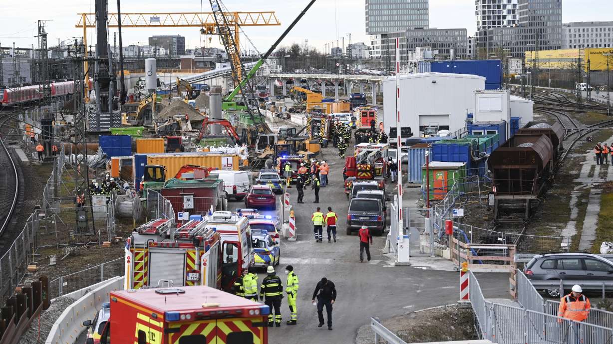 Firefighters, police officers and railway employees stand on a railway site in Munich, Germany, Wednesday. Police in Germany say three people have been injured in an explosion at a construction site next to a busy railway line in Munich.
