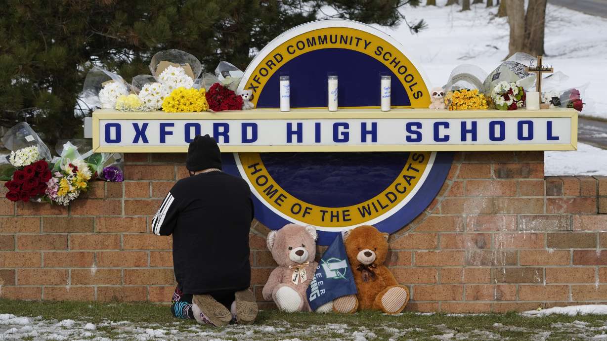 A well-wisher kneels to pray at a memorial on the sign of Oxford High School in Oxford, Mich., Wednesday. A teenager accused of killing four students there was called to the office before the shooting but "no discipline was warranted," the superintendent said Thursday.