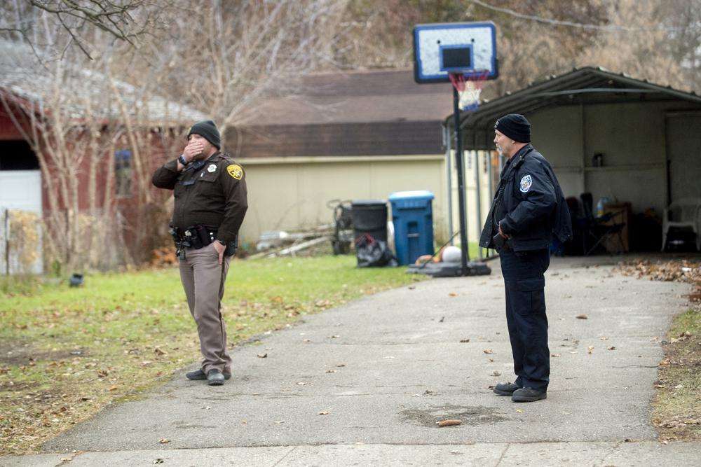 An Oakland County Sheriff's deputy, left, and an Oxford police officer search the grounds outside of the Crumbley residence while seeking James and Jennifer Crumbley, parents of alleged Oxford High School shooter Ethan Crumbley, on Friday, in Oxford, Mich.