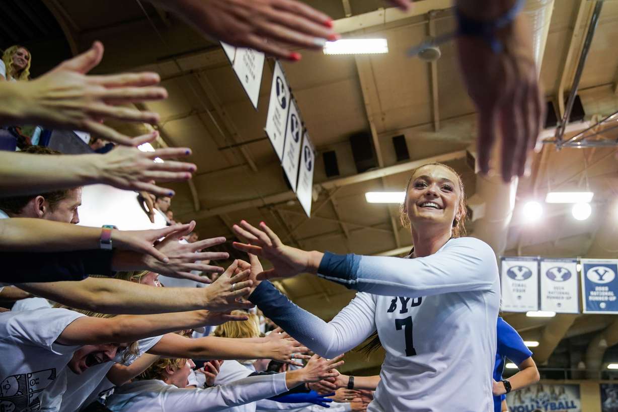 BYU players high-five the fans after winning against Utah in an NCAA volleyball game at Smith Fieldhouse in Provo on Saturday, Dec. 4, 2021.