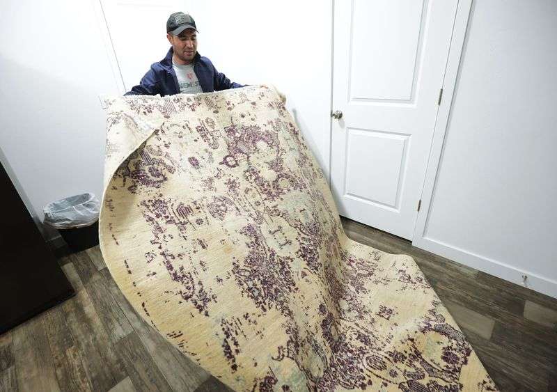Afghan refugee Abdul, who is only providing his first
name since his family is still in Kabul, unrolls an Afghan rug at
his home in Herriman on Thursday, Nov. 18.